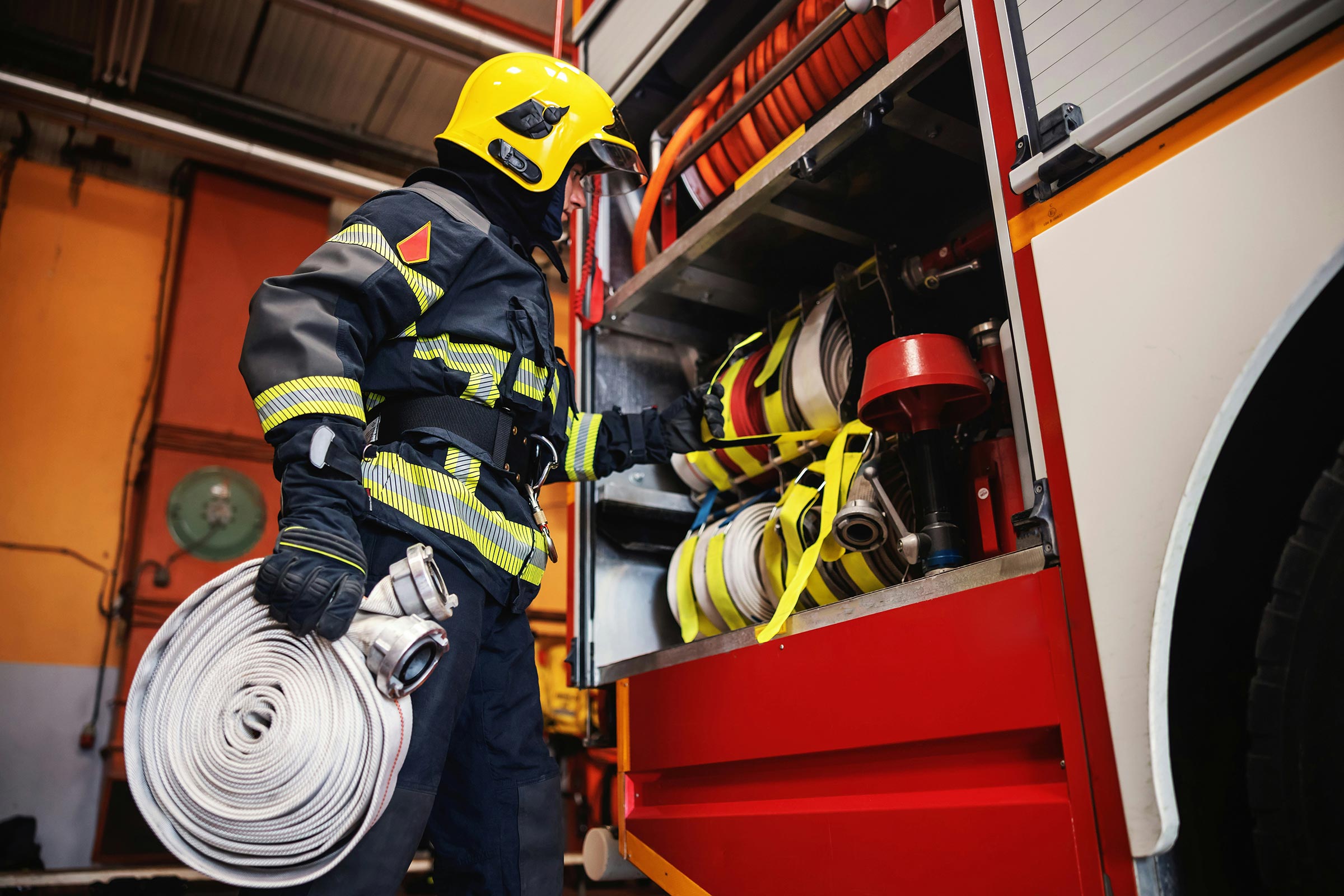 A photograph of a firefighter retrieving equipment from a firetruck